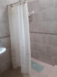 La salle de bains est pourvue d'une douche avec rideau de douche blanc. dans l'établissement Alojamiento en Santa María de Punilla, à Santa María