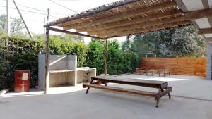 eine Terrasse mit einer hölzernen Pergola und einem Picknicktisch in der Unterkunft Complejo Martins Pilar in Del Viso