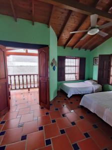 a bedroom with two beds in a room with green walls at Hostal La Pola in Santa Fe de Antioquia