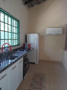 a kitchen with a white refrigerator and a sink at Chácara Recanto Encantado in Cavalcante