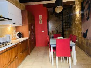 cocina con paredes rojas y mesa con sillas rojas en Authentic House of Character, en Birgu