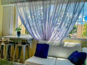 Suite in San Pedro De Macoris في سان بيدرو دي ماكوريس: غرفة معيشة مع أريكة بيضاء ونافذة