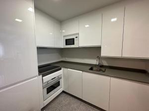 a white kitchen with white cabinets and a sink at Studio 14 + garaje incluido. Nuevo, elegante, acogedor. in Haro +12 photos