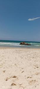 einen Strand mit Fußabdrücken im Sand und im Ozean in der Unterkunft Canto da Natureza in Governador Celso Ramos