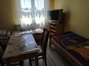Habitación pequeña con mesa y TV. en Pokoje Goscinne Buzuki, en Ciechanów