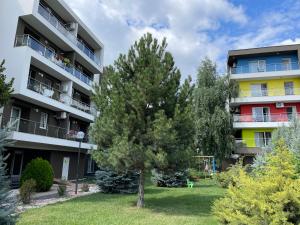 an apartment building with a tree in the yard at Mathias Airport Residences & Therme-Self Check-in in Otopeni