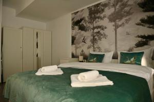 a bedroom with a large bed with towels on it at Mathias Airport Residences & Therme-Self Check-in in Otopeni