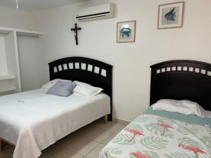 a bedroom with two beds and a cross on the wall at ConVal beach house in Bahía Kino