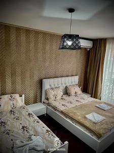 a bedroom with two beds and a pendant light at Conti Hotel & Restaurant in Gjakove