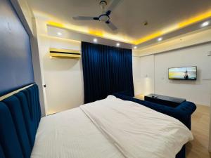 a bedroom with a white bed and a tv at EzyStay Boutique Suites in Lucknow
