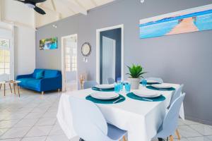 a white dining room with a white table and chairs at Charmante Maison 10min de la mer in Sainte-Anne