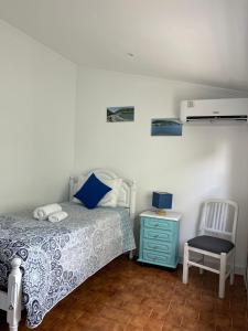 a bedroom with a bed and a blue dresser and a chair at Mar Rosa - Terraço Vista Praia in Horta