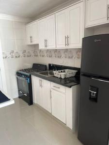 a kitchen with white cabinets and a black refrigerator at Apartamento de Lujo En San Pedro in San Pedro de Macorís