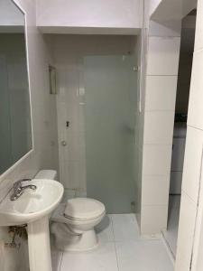 a white bathroom with a toilet and a sink at Apartamento de Lujo En San Pedro in San Pedro de Macorís