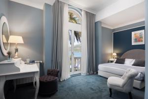 a bedroom with a bed and a desk and a window at Aminess Younique Korcula Heritage Hotel in Korčula