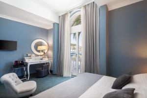 a bedroom with a bed and a desk and a window at Aminess Younique Korcula Heritage Hotel in Korčula