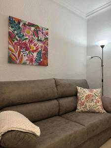 Un sofá en una sala de estar con un cuadro en la pared. en Villa Sol, en Ávila 1 foto más
