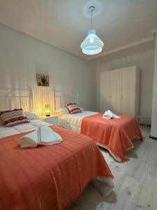 1 dormitorio con 2 camas con sábanas rojas y luz en Villa Sol en Avila