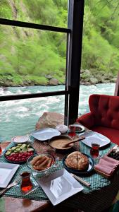 a table with food and a view of a river at AYDER BUNGALOW - river view , Royal Bungalow Resorts in Çamlıhemşin