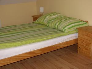 a bed with a green blanket and a wooden dresser at Hunyadi Apartment in Kalocsa