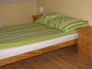 カロチャにあるHunyadi Apartmentのベッド(緑の毛布、木製ドレッサー付)