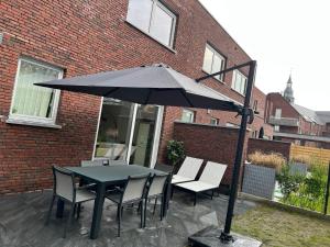 een tafel en stoelen onder een parasol op een patio bij Lou&Hans in Aalst