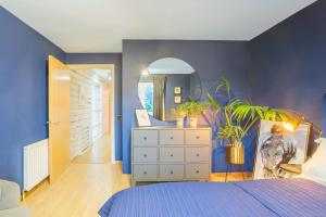 a blue bedroom with a dresser and a mirror at Luxurious House With Garden in Perth