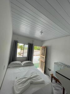 a white bed in a room with a window at Pousada Cattleya in Presidente Figueiredo