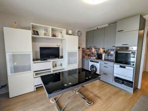 a kitchen with white cabinets and a black desk at Le Petit Sapin in Xonrupt-Longemer