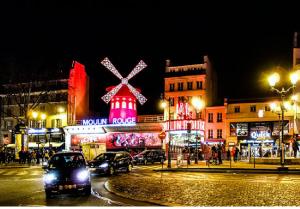 Una ciudad de noche con coches conduciendo por una calle en Appartement situé dans le 9ème arrondissement, à deux pas du Sacré-Coeur, en París