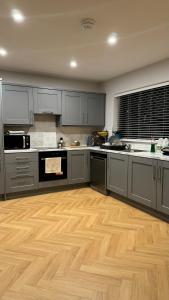 a large kitchen with wooden floors and gray cabinets at Large bedroom near to the center 