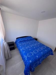 a bed in a room with a blue blanket on it at Casa Playa Loreto in Caldera