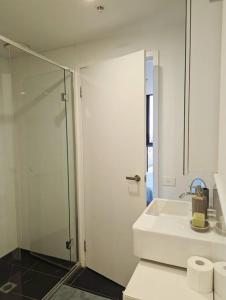 a bathroom with a sink and a glass shower at Breathtaking views of Yarra River and City skyline with Free parking Gym access in Melbourne