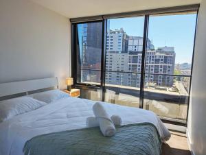 een slaapkamer met een wit bed en een groot raam bij Breathtaking views of Yarra River and City skyline with Free parking Gym access in Melbourne