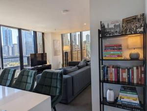 een woonkamer met een bank en een plank met boeken bij Breathtaking views of Yarra River and City skyline with Free parking Gym access in Melbourne