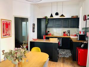 a kitchen with black cabinets and a wooden table at Maison de Maître avec grande terrasse au Centre-Ville in Perpignan