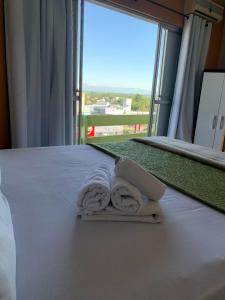 two towels on a bed with a large window at Simar Hotel in Araranguá