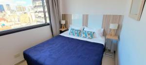 un letto blu in una stanza con finestra di Pacifico Apartment a Buenos Aires