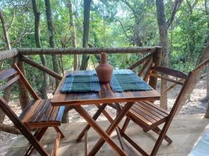 una mesa de madera con un jarrón en el porche en RECANTO DO SENTIR, conexão com a natureza e muita paz. en Praia do Forte