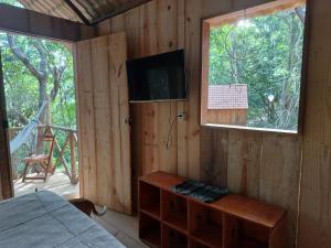 Zimmer mit einem Bett, einem TV und einem Fenster in der Unterkunft RECANTO DO SENTIR, conexão com a natureza e muita paz. in Praia do Forte