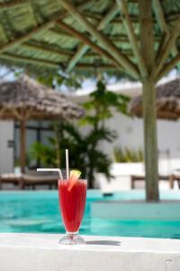 a drink sitting on a table next to a pool at Casa DantesVoyage - SPA in Nungwi