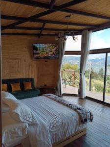 a bedroom with a bed and a large window at Glamping Caelum. Refugio al aire libre, en Macheta Cundinamarca in Machetá