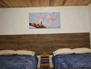 a bedroom with two beds and a picture on the wall at Cabaña La Camelia in Creel