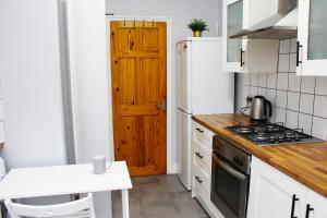 Modern ground floor flat - 15 min to Central London في لندن: مطبخ بدولاب بيضاء وباب خشبي