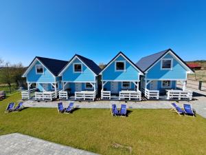 duży niebieski dom z krzesłami i krzesłami ogrodowymi w obiekcie Błękitne Zamorze w mieście Niechorze