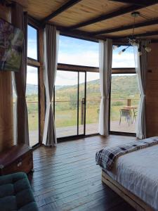 um quarto com uma cama e uma grande janela em Glamping Caelum. Refugio al aire libre, en Macheta Cundinamarca em Machetá