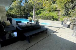 a patio with a bench and an umbrella and a pool at Bright and cheerful 3 Bed-3 Bath house with pool in Los Angeles