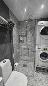 a bathroom with a shower and a toilet and a washing machine at Attic floor with views over fields and sea in Sigtuna +25 photos