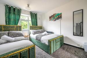 Duas camas num quarto com cortinas verdes e um espelho em *RA26S* For your most relaxed & Cosy stay + Free Parking + Free Fast WiFi * em Adel