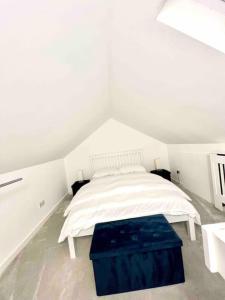 a white bedroom with a bed and a blue stool at Recently renovated,modern house. train station in North Mimms